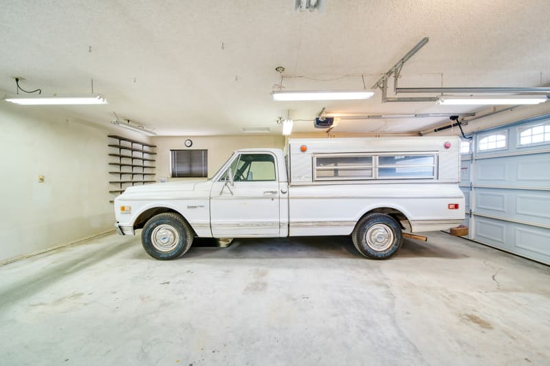 A white 1970s pickup alone in a swept, well-lit home garage.