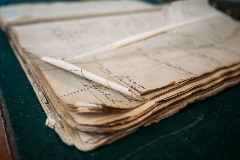 An open antique ledger with ruled columns, handwritten entries, and a pencil laid across the page.