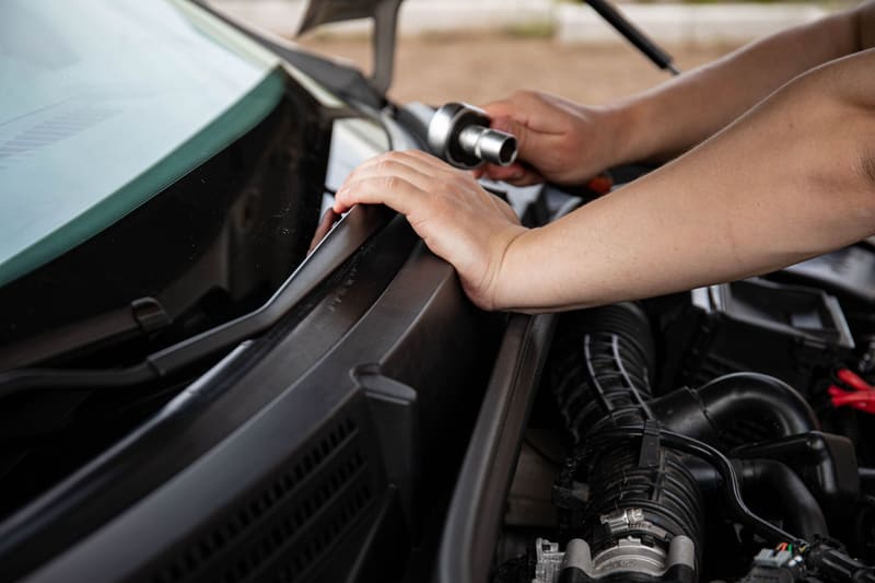 Hands working a socket wrench at the engine bay.