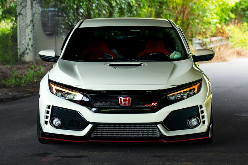A white hatchback photographed head-on and low under a concrete underpass.